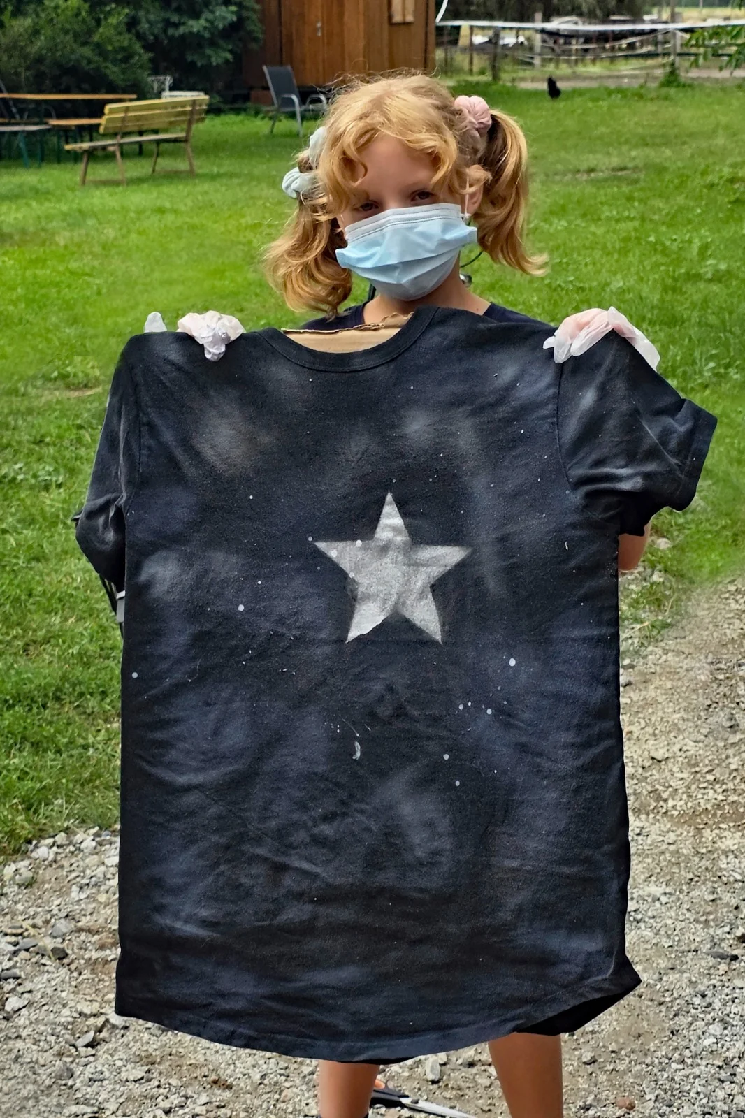 Ein Kind zeigt ein selbst gestaltetes T-Shirt mit Sternmotiv