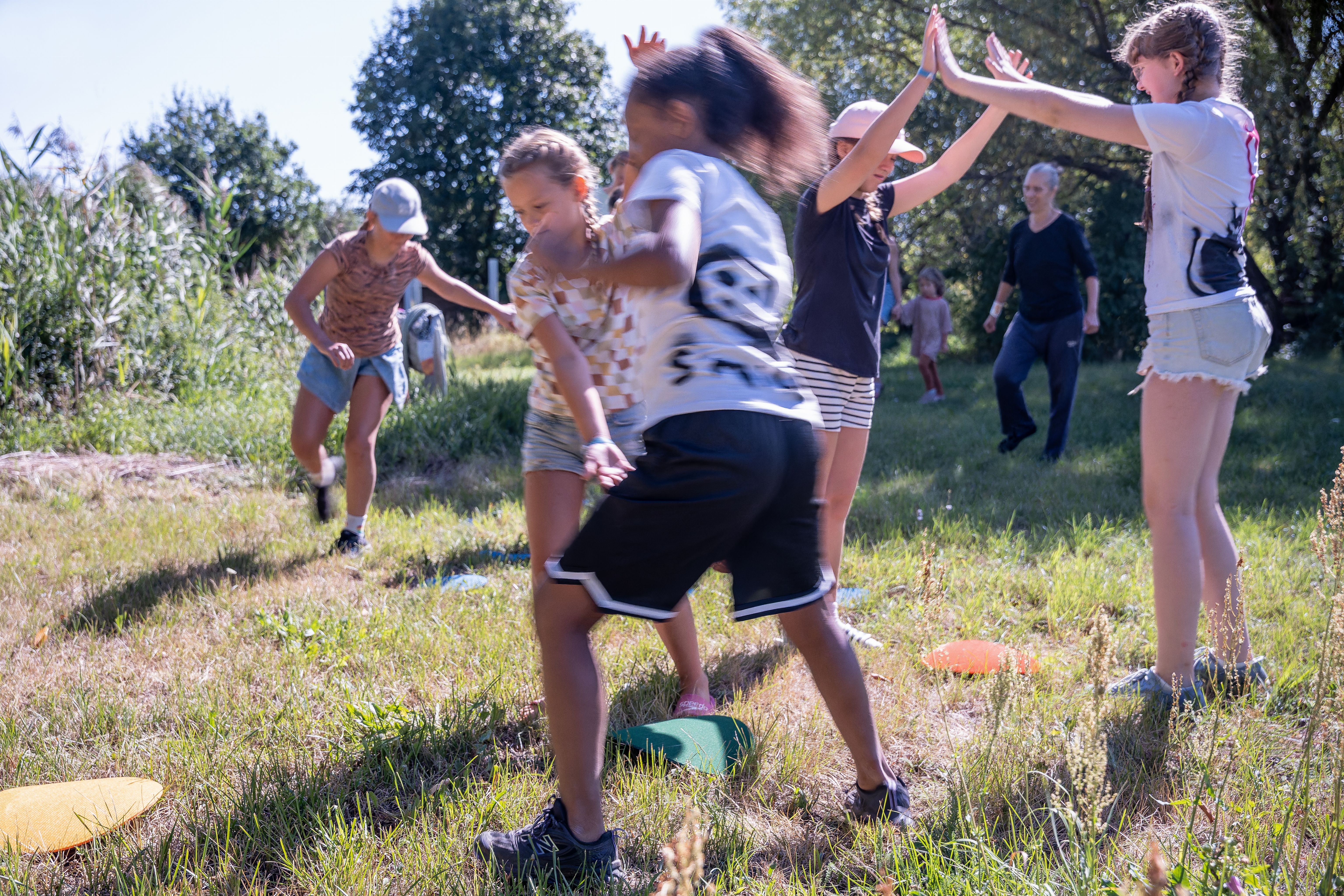 Kindergruppe beim Bewegungsspiel auf der Wiese mit farbigen Bodenmarkierungen