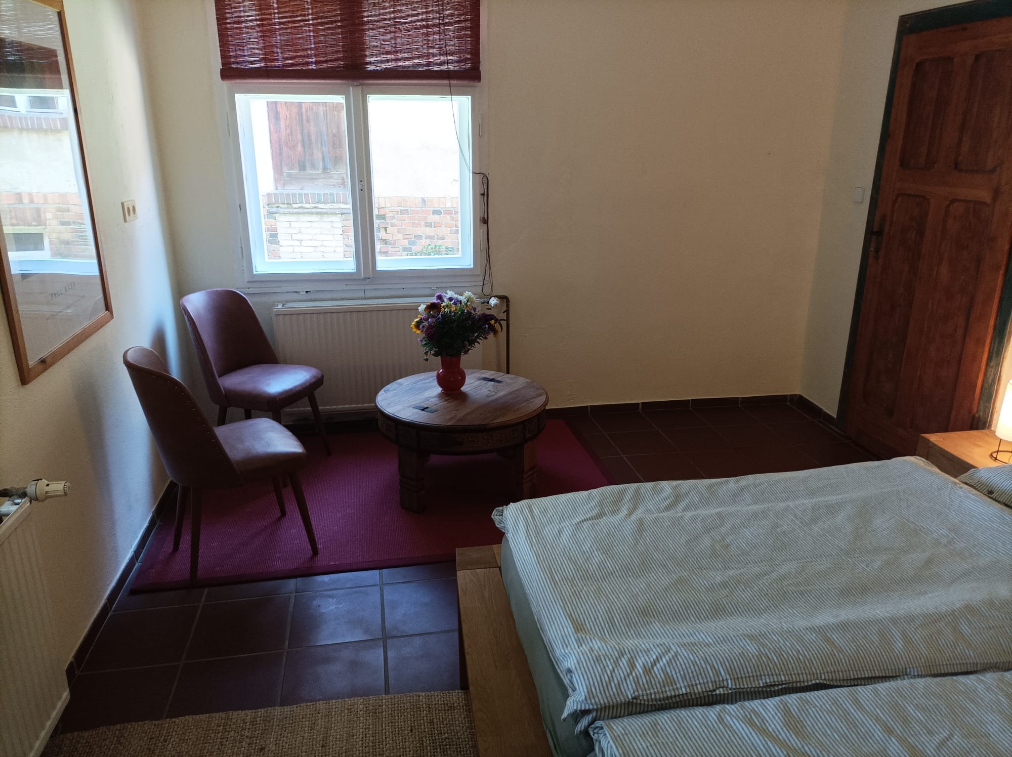Sitzecke mit zwei rosa Lederstühlen und rundem Holztisch mit Blumenstrauß im Zimmer Kalinka
