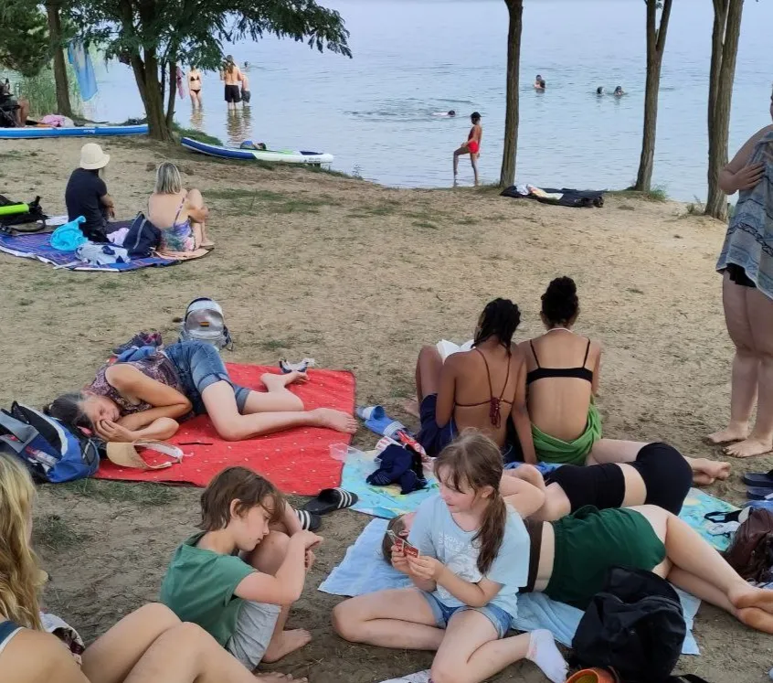 Eine Gruppe sitzt an einem Sommertag am Ufer des Badesees